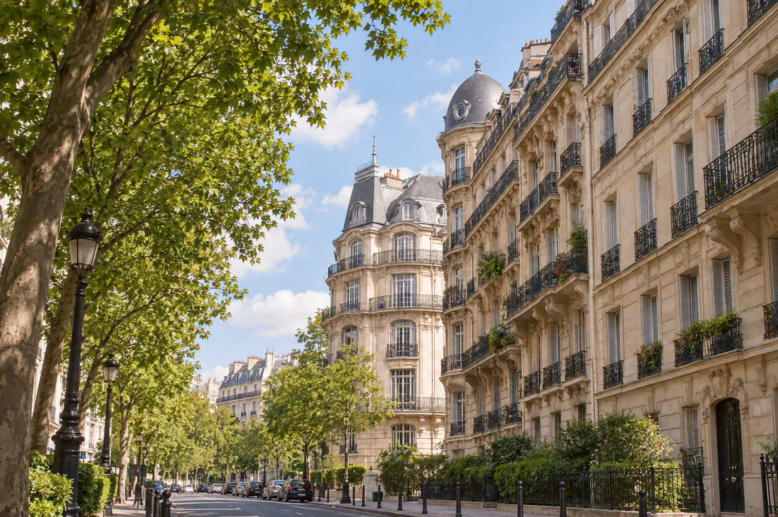 Rue arborée bordée d'immeubles haussmanniens à balcons fleuris, Paris 16e