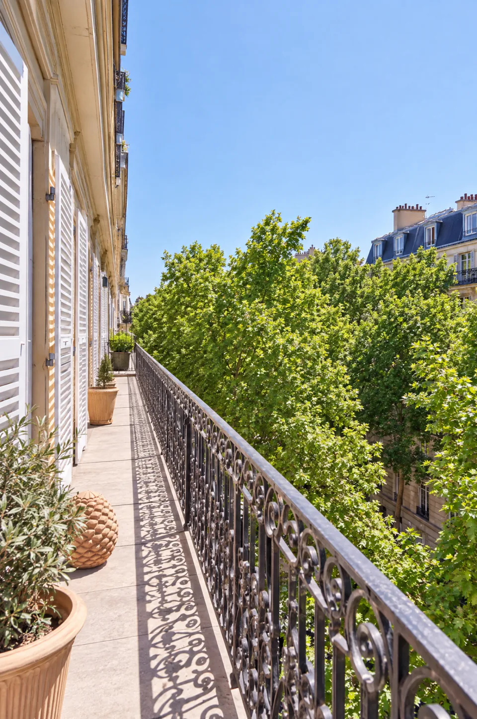 Balcon filant en fer forgé sur une rue arborée de Paris