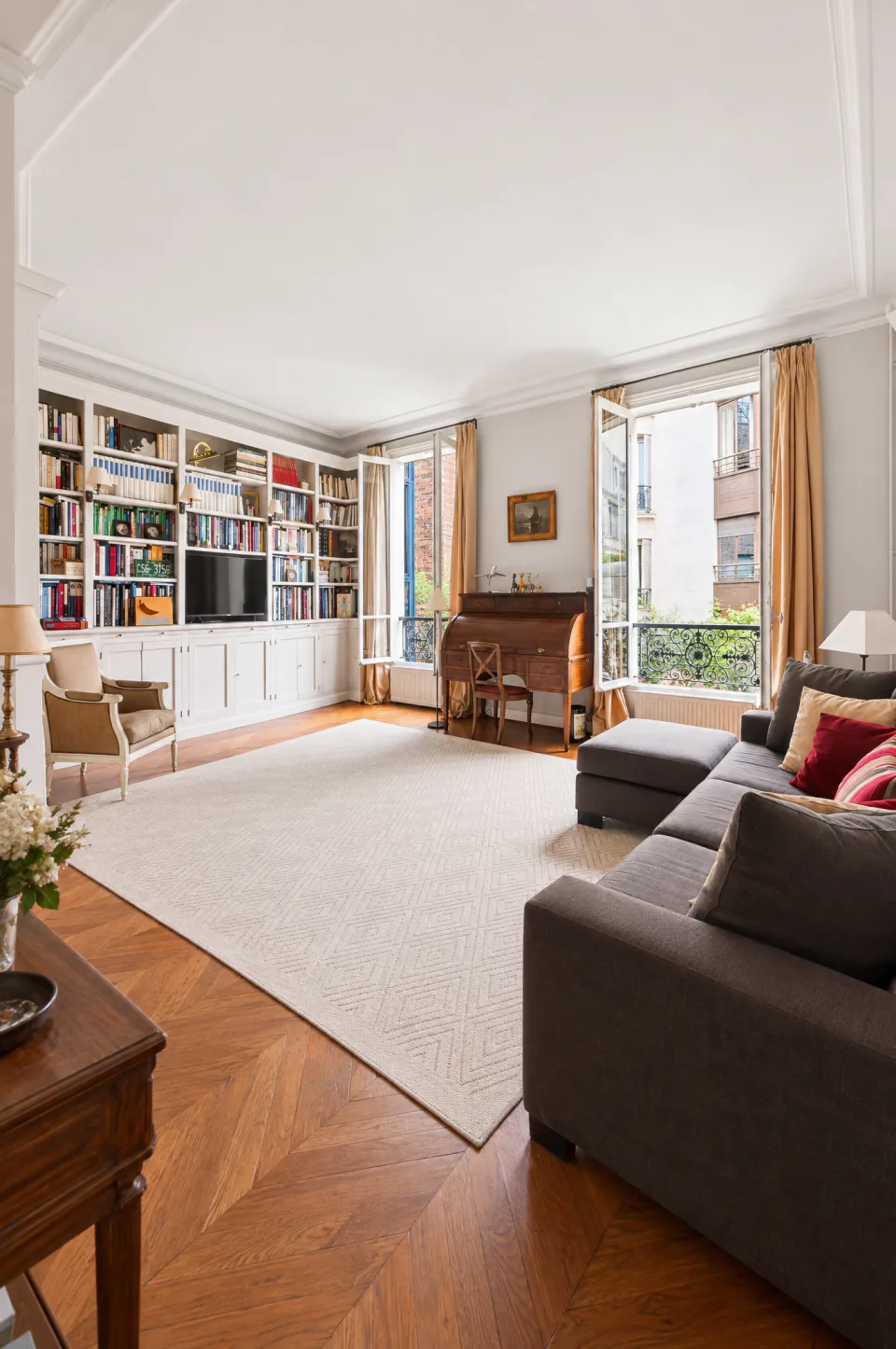Salon avec bibliothèque, bureau ancien et fenêtres sur cour
